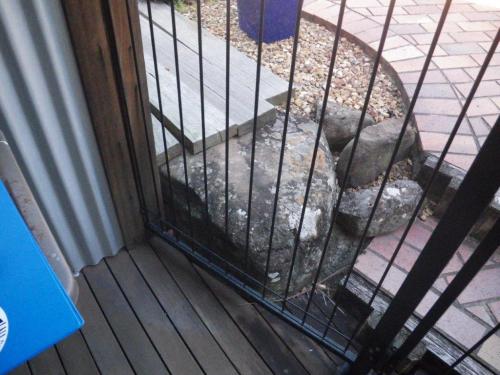 A large rock, timber sleepers & raised step are within 300mm of the base of the inside of a pool fence