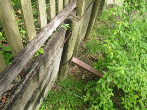 What’s holding this retaining wall up? Metal stay provides foothold onto horizontal threaded rod, onto top of sleeper wall & onto the illegal height timber paling fence